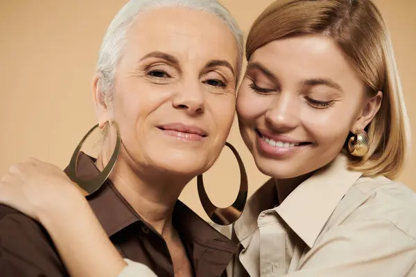 Una mujer madura comparte un momento de corazón con su hija adulta sonriente. - foto de stock