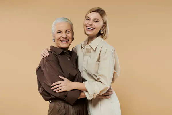 A mature woman and her adult daughter share a warm embrace, smiling brightly. — Stock Photo