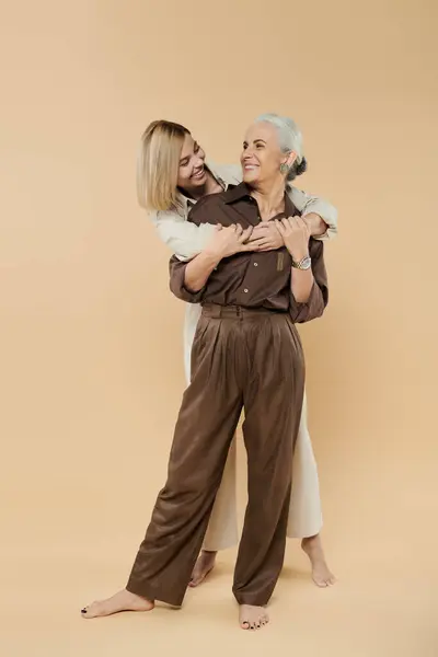 A mature woman and her adult daughter share a warm embrace, laughing together. — Stock Photo