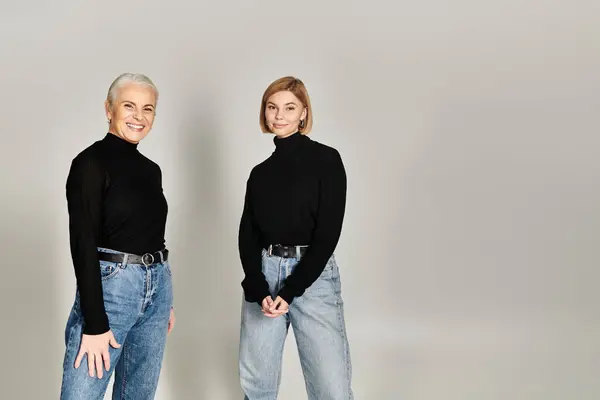 A mature woman and her adult daughter share a joyful moment in matching attire. — Stock Photo
