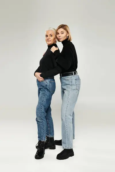 A mature woman and her adult daughter embrace, showcasing their fashion sense. — Stock Photo