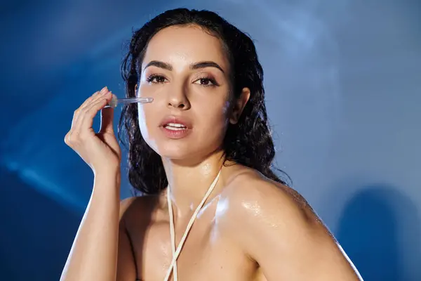 A young woman applies serum, highlighting her skincare routine with elegance. — Stock Photo