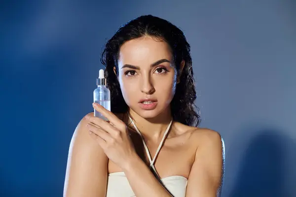 A young woman poses confidently while holding a skincare serum. — Stock Photo