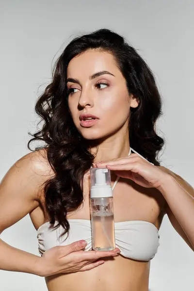 Bella donna dimostra la sua routine di cura della pelle con colori vivaci intorno a lei. — Foto stock