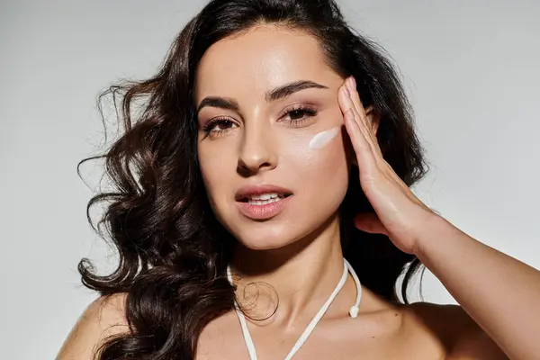 A beautiful woman applies skincare product with confidence and grace. — Stock Photo