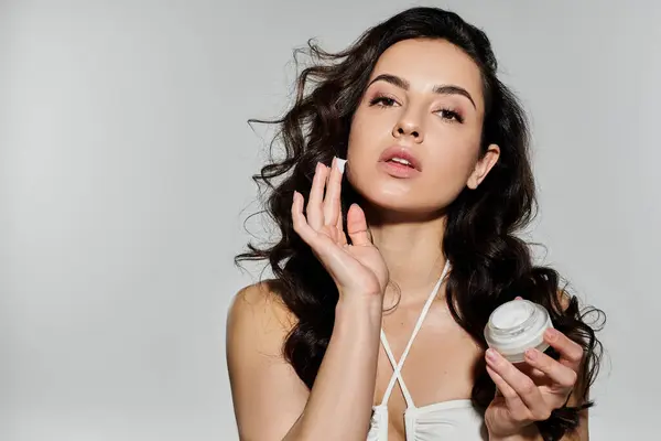 Beautiful woman applying skincare with confidence and style in a colorful setting. — Stock Photo