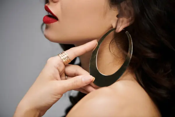 A beautiful woman poses while highlighting her stylish earrings. — Stock Photo