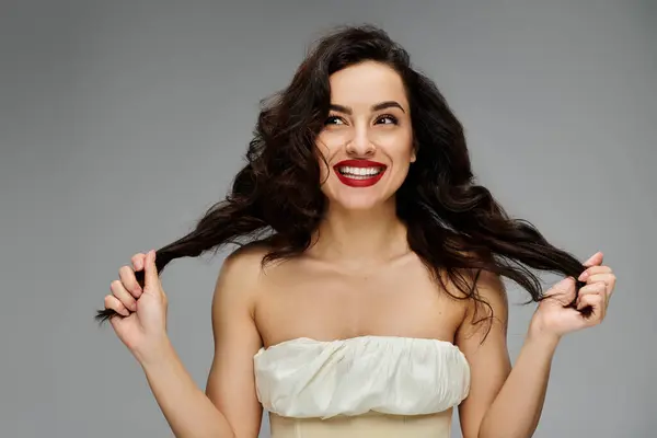 Young woman poses gracefully on gray backdrop. — Stock Photo