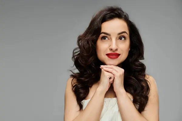 Cheerful woman poses gracefully on gray backdrop. — Stock Photo