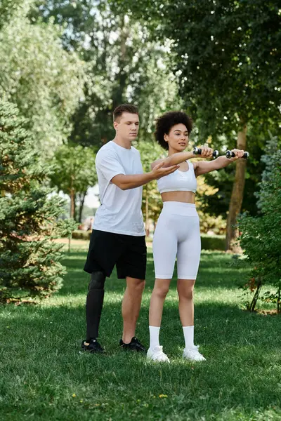 Una joven y su amiga hacen ejercicio juntos, centrándose en el entrenamiento de fuerza en un parque vibrante. - foto de stock