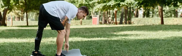 Hombre con discapacidad que hace ejercicio al aire libre, mostrando fuerza e inclusividad en un animado entorno de parque. - foto de stock