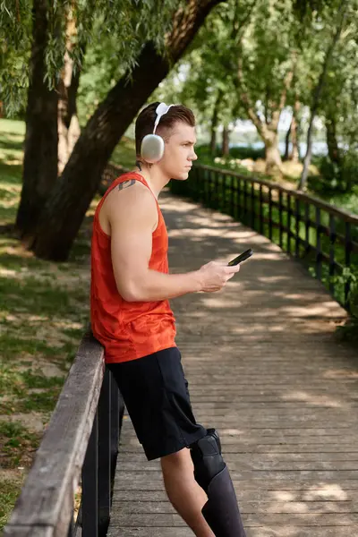A young man with prosthetic leg using smartphone, surrounded by park greenery. — Stock Photo