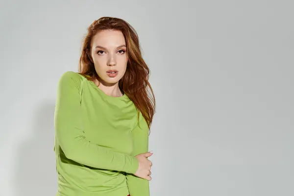 A red haired woman showcases her fashionable outfit with a confident pose. — Stock Photo