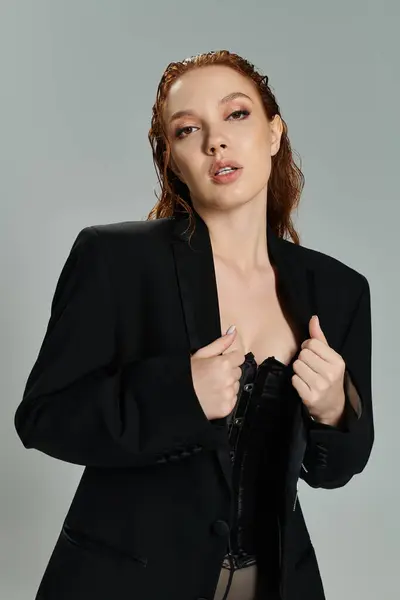 A confident woman in fashionable attire showcases her striking red hair and style. — Stock Photo