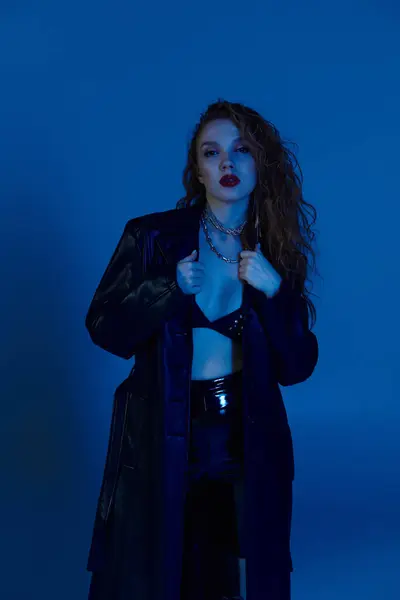 Une femme confiante met en valeur ses prouesses de la mode dans un cadre lumineux bleu magnifique. — Photo de stock