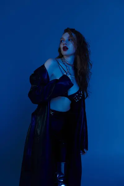 Una mujer pelirroja de moda exhibe su estilo en un ambiente azul cautivador. — Stock Photo
