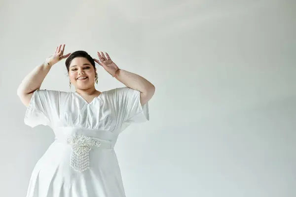 A radiant plus size bride radiates joy in her white wedding dress, elegantly framed by a grey background. — Stock Photo