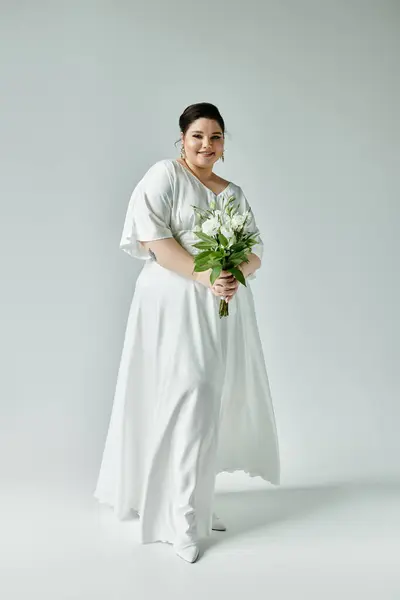 A stunning bride radiates confidence in a flowing white gown while holding a beautiful bouquet. — Stock Photo