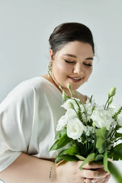 A stunning bride holds a bouquet of white flowers, exuding confidence and grace in her flowing wedding dress. — Stock Photo