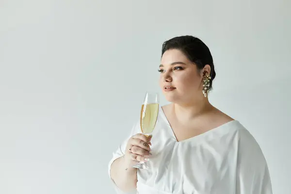 A beautiful bride in a flowing gown raises a glass of champagne, radiating joy in a serene setting. — Stock Photo