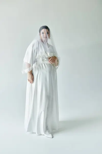 A beautiful young bride radiates joy in her white gown, adorned with graceful earrings and a flowing veil. — Stock Photo