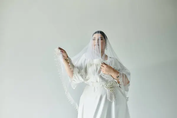 A stunning young woman in a white gown and earrings gracefully poses, showcasing her bridal elegance. — Stock Photo