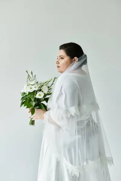 A stunning bride holds a bouquet, adorned in a beautiful gown and veil, radiating elegance and grace. — Stock Photo