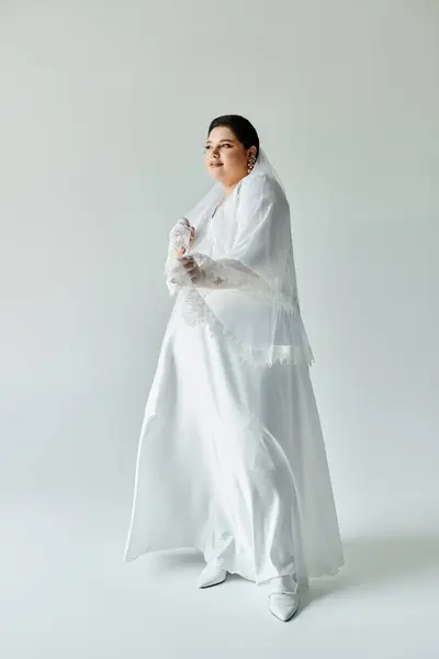 The beautiful bride beams with joy in her exquisite gown and elegant earrings against a minimalist grey background. — Stock Photo