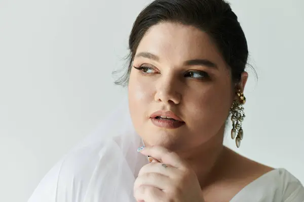 A beautiful plus size bride poses gracefully, showcasing her exquisite gown and sparkling earrings. — Stock Photo