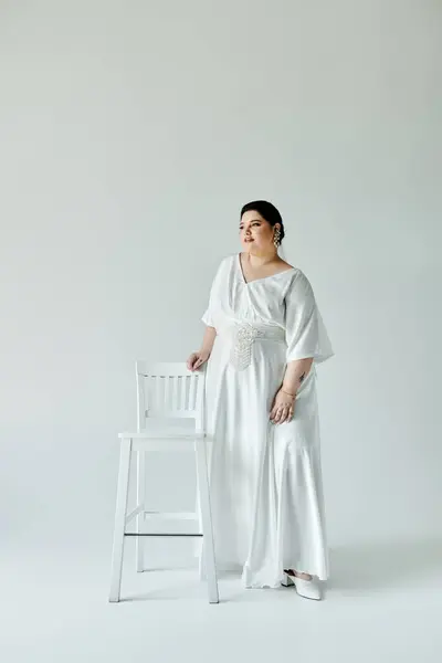 Una bella sposa plus-size si erge con fiducia, ornata con un abito elegante ed eleganti orecchini. — Stock Photo