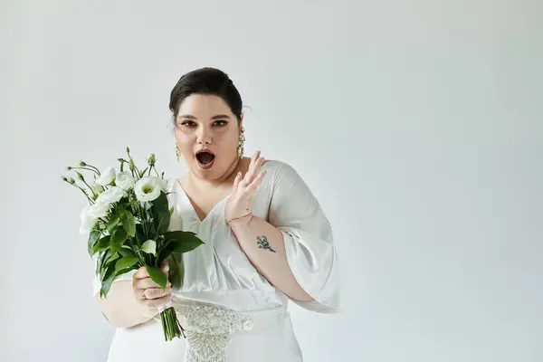 Incroyable mariée de taille plus dans une magnifique robe vagues tout en tenant un bouquet de fleurs fraîches. — Photo de stock