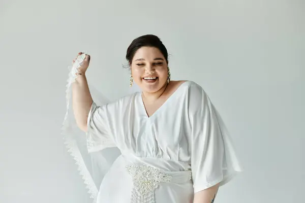 A radiant young bride showcases her beautiful wedding dress and earrings, exuding happiness in a serene setting. — Stock Photo