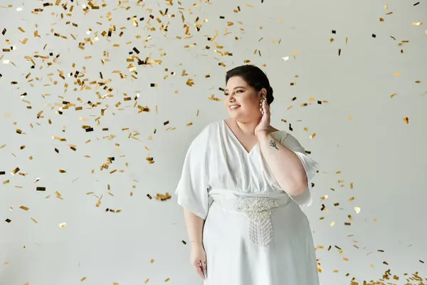 Una sposa gioiosa in un abito bianco fluente brilla di felicità in una cascata di coriandoli d'oro. — Foto stock