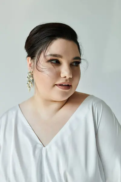 A radiant plus size bride showcases her beauty in a flowing white dress adorned with sparkling earrings. — Stock Photo