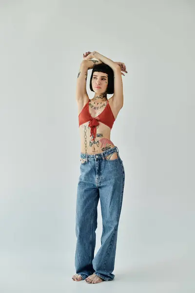 Una joven confiada exhibe sus tatuajes y atuendo de moda con una pose llamativa. - foto de stock