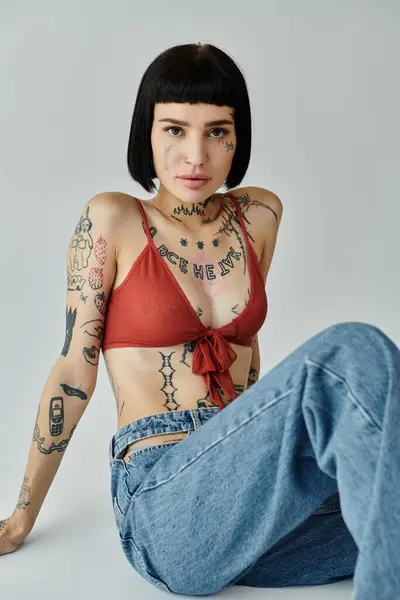 A stylish woman showcases her tattoos while sitting gracefully. — Stock Photo