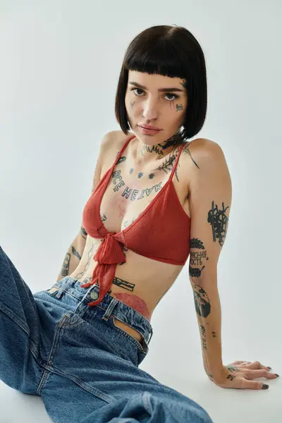 A fashionable young woman showcases her tattoos in a creative pose. — Stock Photo