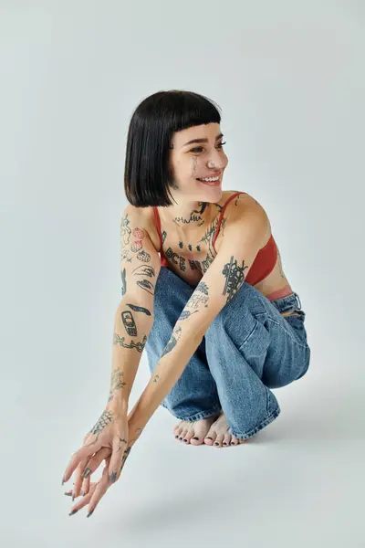 A stylish woman with tattoos plays with her hair, smiling happily. — Stock Photo