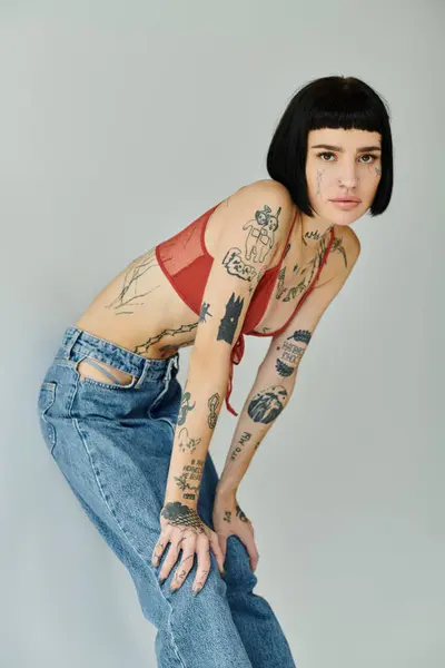 A stylish woman showcases her tattoos and fashionable outfit with poise. — Stock Photo
