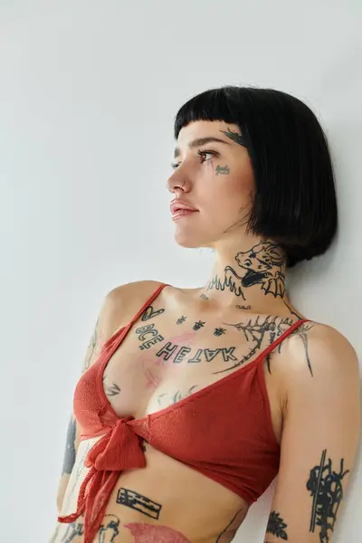 A stylish woman with intricate tattoos leans gracefully against the wall. — Stock Photo