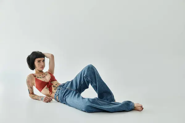 A fashionable woman showcases her tattoos while relaxing on the floor. — Stock Photo