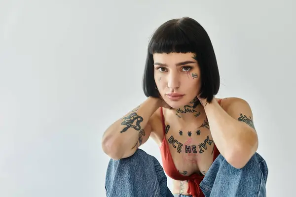 Une femme élégante ornée de tatouages pose avec confiance, mettant en valeur son expression unique. — Photo de stock