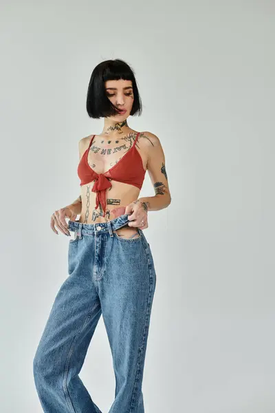 Mujer joven de moda presenta con confianza sus tatuajes y atuendos únicos. - foto de stock