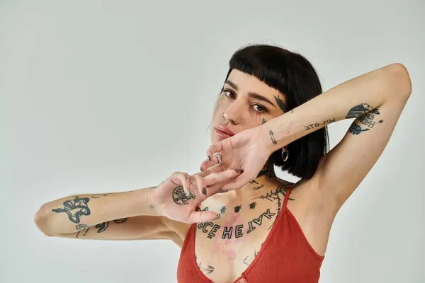 A young woman showcases her tattoos while striking a fashionable pose. — Stock Photo