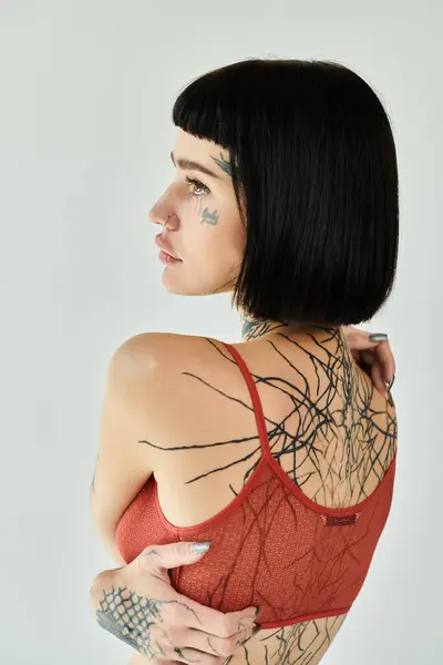 A stylish young woman showcases her intricate tattoos with confidence. — Stock Photo