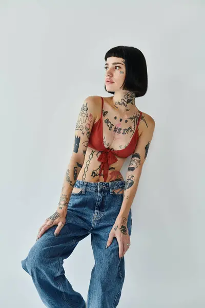 A fashionable woman poses confidently, highlighting her vibrant tattoos and chic attire. — Stock Photo