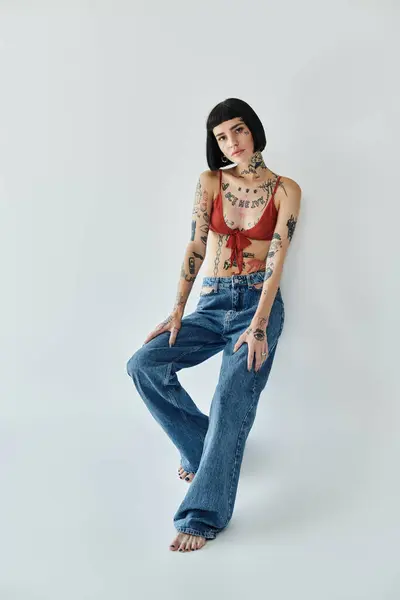 Young woman showcases her tattoos in trendy attire and a chic stance. — Stock Photo