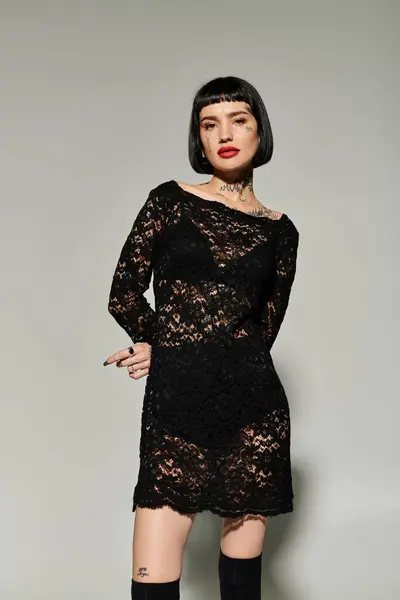 A young woman showcases her tattoos in fashionable black lace clothing. — Stock Photo