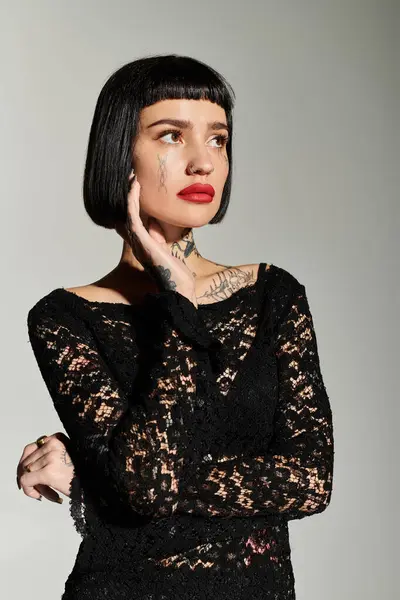 A fashionable woman showcases her tattoos and bold makeup with an artistic pose. — Stock Photo