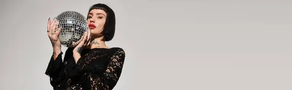 A fashionable woman holds a sparkling disco ball with confidence. — Stock Photo
